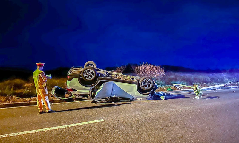 Chiếc taxi lật ngửa sau khi t&ocirc;ng g&atilde;y trụ đ&egrave;n - Ảnh: AB.