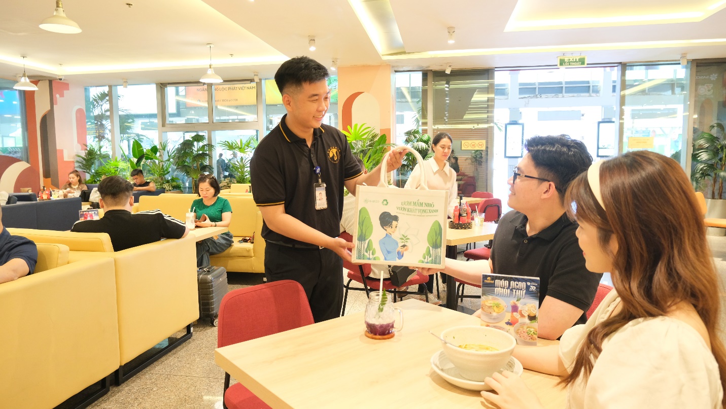 SASCO khởi động chiến dịch "Ươm mầm khát vọng xanh"- Ảnh 6. A person holding a bag with a sign in front of a group of people Description automatically generated