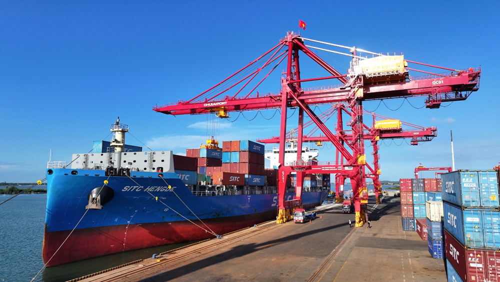 A large red crane and a ship  Description automatically generated