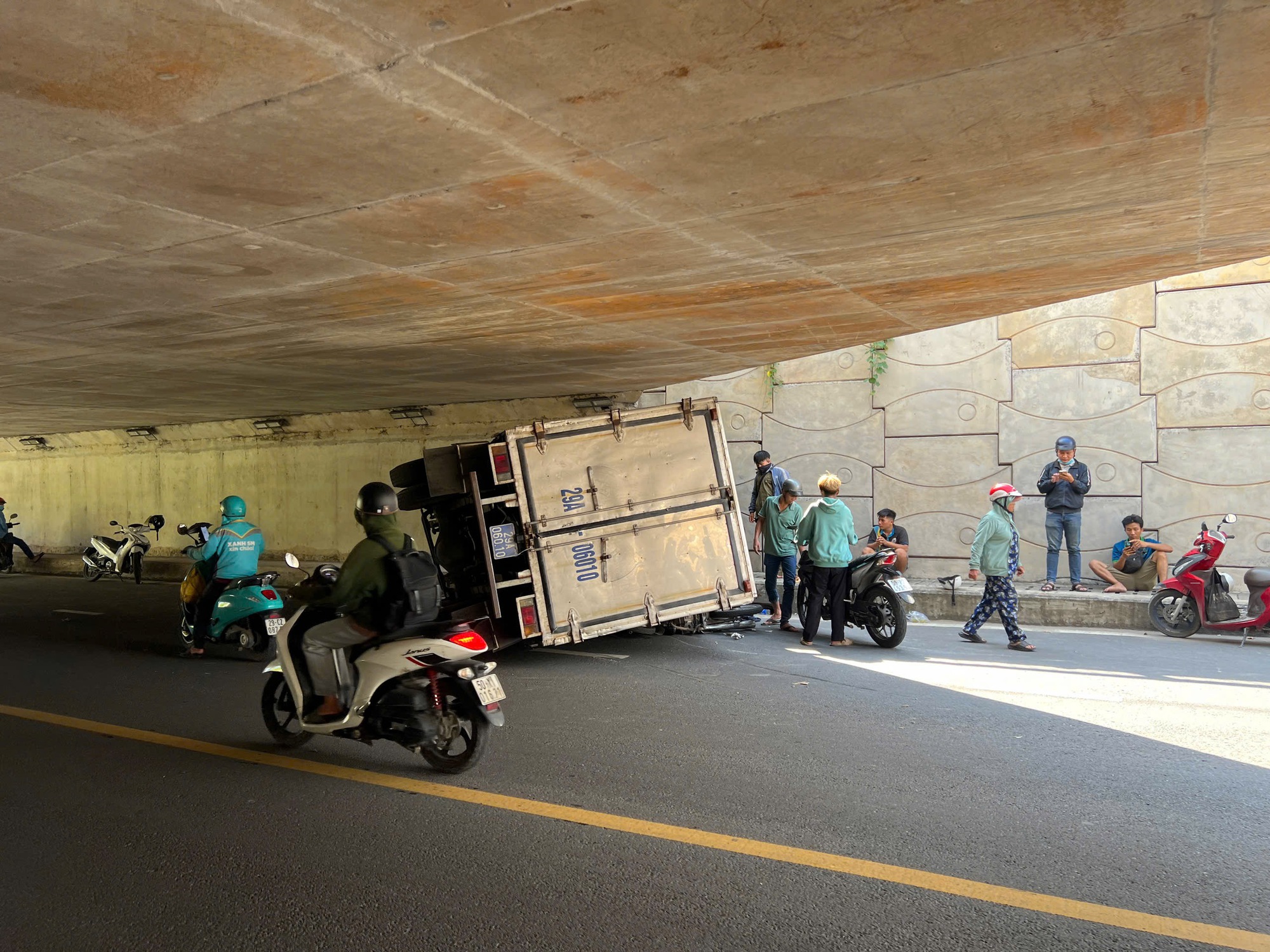 TP.HCM: Xe tải va v&agrave;o th&agrave;nh cầu hầm chui rồi lật nh&agrave;o, đ&egrave; tr&uacute;ng 2 xe m&aacute;y- Ảnh 1.