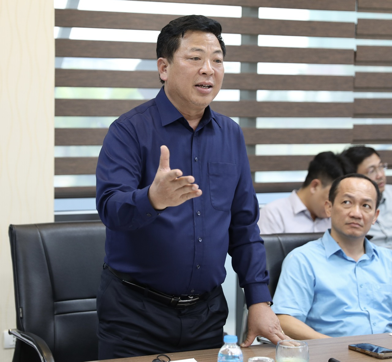 A person standing in front of a table with other people in the background  AI-generated content may be incorrect.