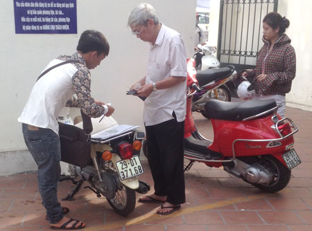 Một &ldquo;c&ograve;&rdquo; (ngo&agrave;i c&ugrave;ng, b&ecirc;n tr&aacute;i) đang giao dịch với kh&aacute;ch tại điểm đăng k&yacute; Hai B&agrave; Trưng, H&agrave; Nội