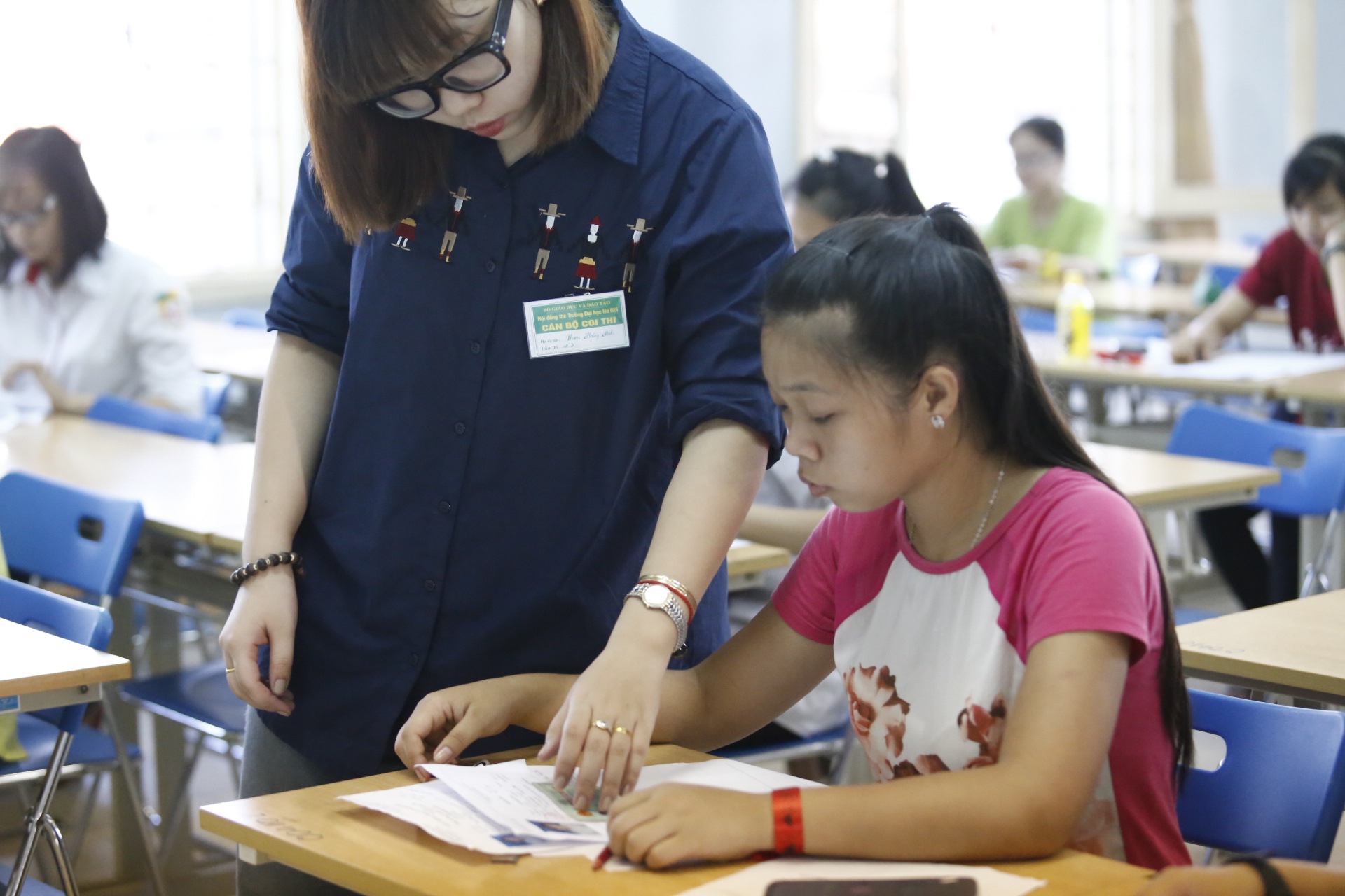 Gi&aacute;m thị kiểm tra giấy tờ của c&aacute;c th&iacute; sinh lần cuối, đồng thời k&yacute; t&ecirc;n v&agrave; nhắc nhở th&iacute; sinh một v&agrave;i kh&acirc;u thủ tục trước khi đến giờ thi.