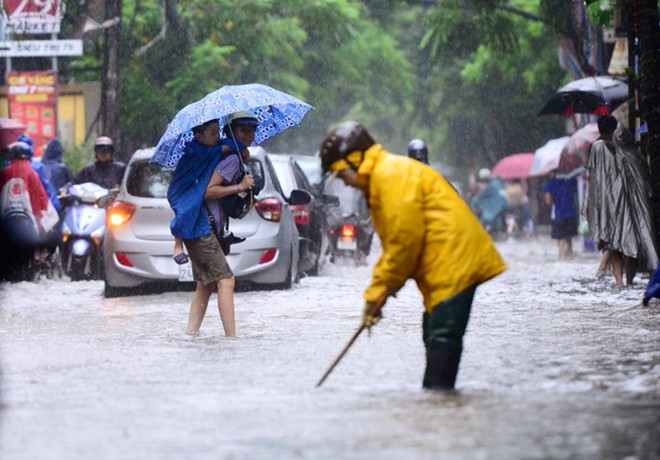 Một phụ huynh c&otilde;ng con vượt nước ngập tới trường.