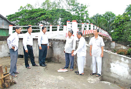 Anh Huỳnh Văn Bằng, Chủ tịch x&atilde; Trung Hưng (thứ ba từ tr&aacute;i sang) đang trao đổi c&ocirc;ng việc với Ban từ thiện x&atilde; Trung Hưng ở c&acirc;y cầu 3/2