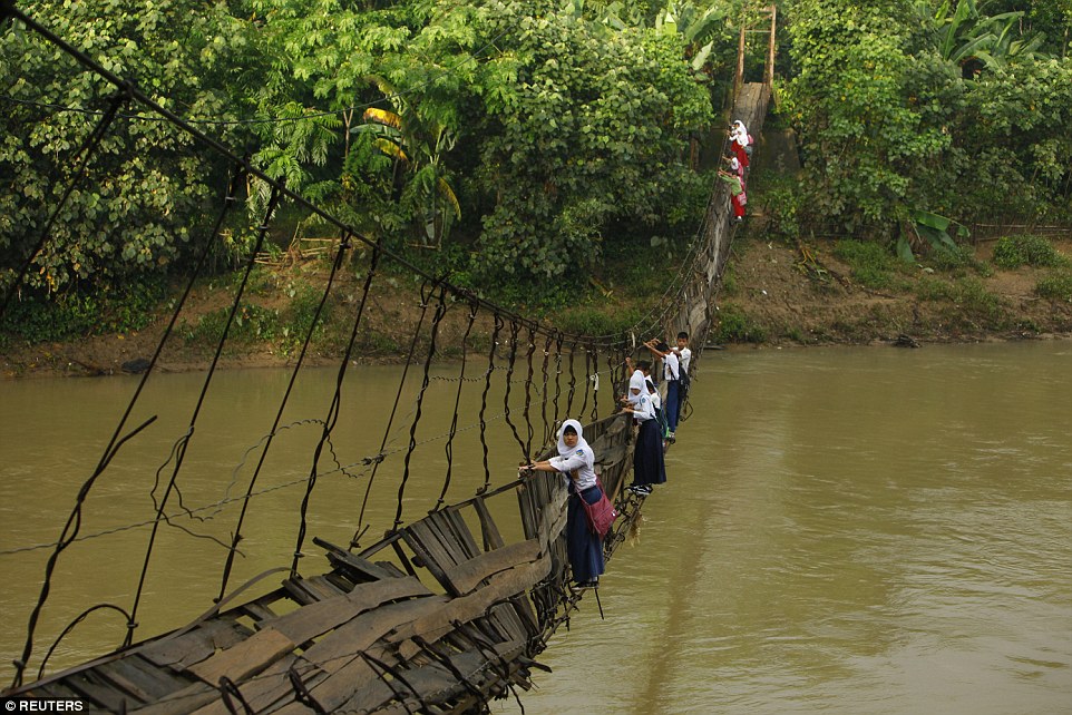 Học sinh tại Indonesia b&aacute;m c&aacute;c thanh sắt tr&ecirc;n c&acirc;y cầu bị g&atilde;y vượt s&ocirc;ng Ciherang, gần l&agrave;ng Lebak Regency.