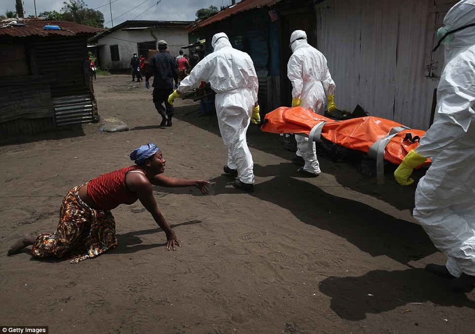 Một người phụ nữ kh&oacute;c ngất, b&ograve; tới thi thể người chị vừa qua đời v&igrave; Ebola trong khi đội cứu hộ đang đưa thi thể đi ch&ocirc;n