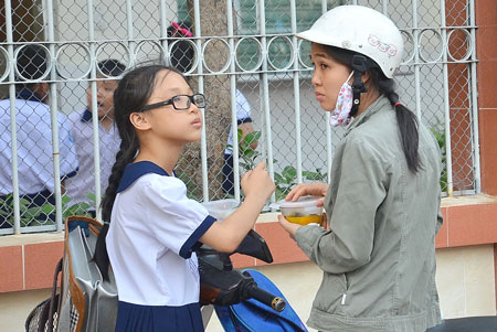 Một phụ huynh tranh thủ cho con ăn bữa chiều trước giờ học th&ecirc;mẢnh: NLĐ