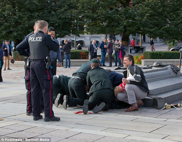 Mọi người sơ cứu cho người l&iacute;nh bị bắn khi đang đứng g&aacute;c tại đ&agrave;i tưởng niệm, nhưng do vết thương qu&aacute; nặng anh đ&atilde; kh&ocirc;ng qua khỏi