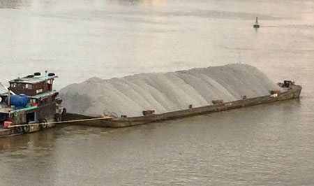 Một chiếc s&agrave; lan chở đầy ắp đ&aacute; sau khi rời b&atilde;i tập kết vật liệu x&acirc;y dựng dưới ch&acirc;n cầu H&oacute;a An