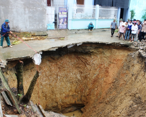 Một người d&acirc;n ph&ograve;ng đang d&ugrave;ng d&acirc;y buộc v&agrave;o vi&ecirc;n gạch để đo độ s&acirc;u của hố