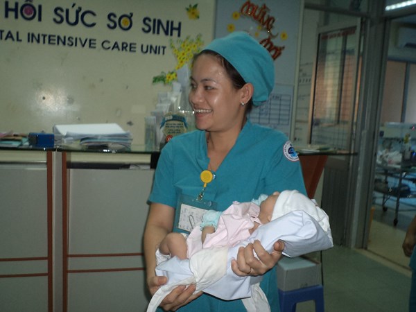 Điều dưỡng của Khoa hồi sức sơ sinh, Bệnh viện Nhi đồng 1 đưa bé Nguyễn Quốc Huy từ phòng hồi sức ra ngoài cho cha gặp.