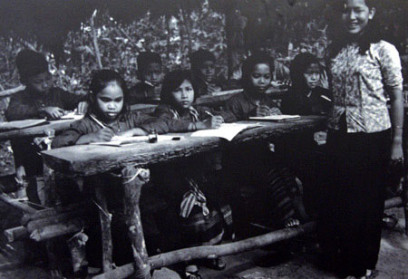 D&ugrave; điều kiện vật chất thiếu thốn, b&agrave;n ghế được gh&eacute;p tạm bợ từ những c&acirc;y rừng nhưng c&ocirc; tr&ograve; đều rất vui vẻ v&agrave; cố gắng. Đ&acirc;y l&agrave; một lớp học dưới l&aacute;n thời chiến