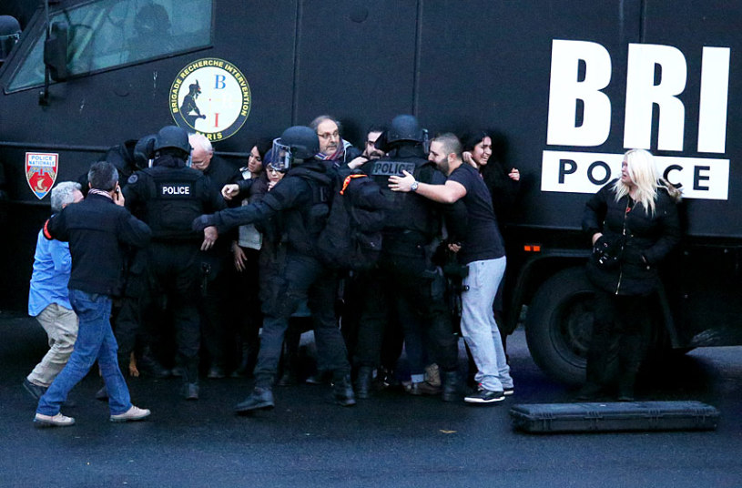 Những con tin được cứu tho&aacute;t được tập trung đằng sau xe bọc th&eacute;p b&ecirc;n ngo&agrave;i si&ecirc;u thị 