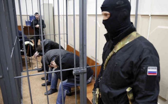 Ba nghi phạm bị nhốt trong lồng sắt.