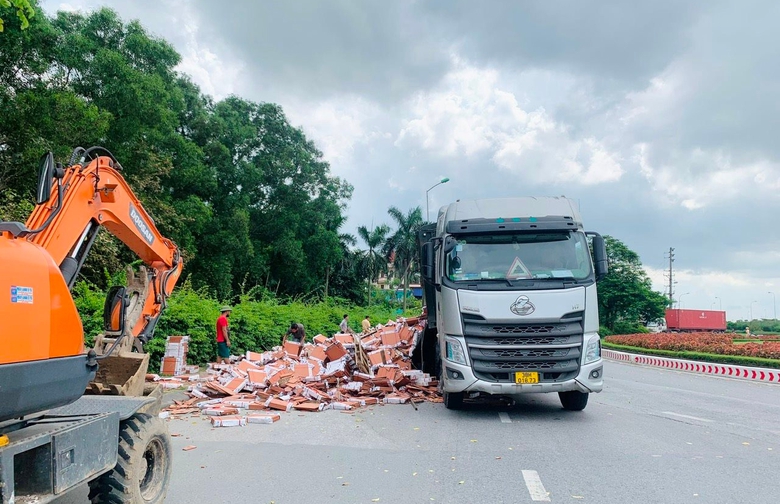 Th&ugrave;ng xe container bất ngờ bật chốt, h&agrave;ng ngh&igrave;n tấm gạch rơi xuống đường- Ảnh 1.