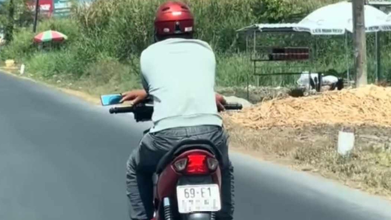 Người đ&agrave;n &ocirc;ng thản nhi&ecirc;n bắt ch&eacute;o tay điều khiển xe m&aacute;y tr&ecirc;n quốc lộ 1- Ảnh 1.