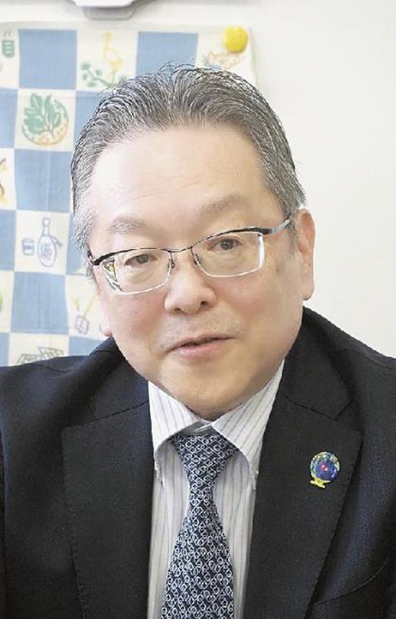 メガネをかけたスーツ姿の男性  自動的に生成された説明