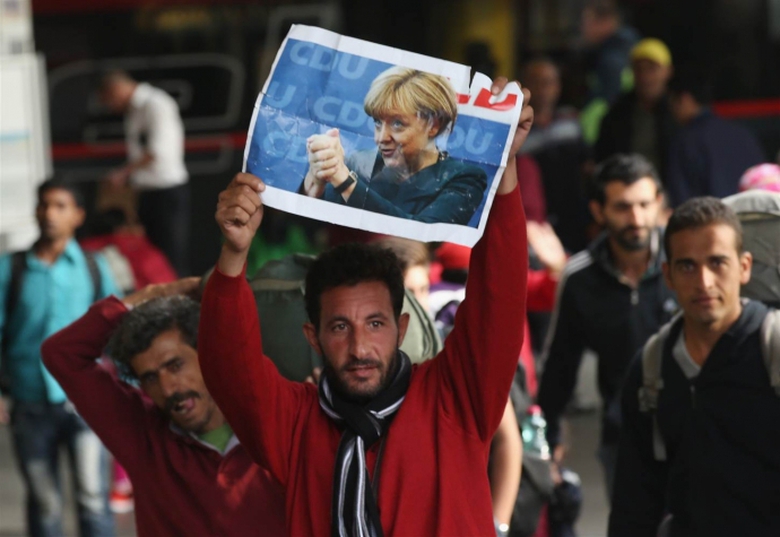 Một người tị nạn ở TP Munich Đức giơ cao ảnh b&agrave; Me