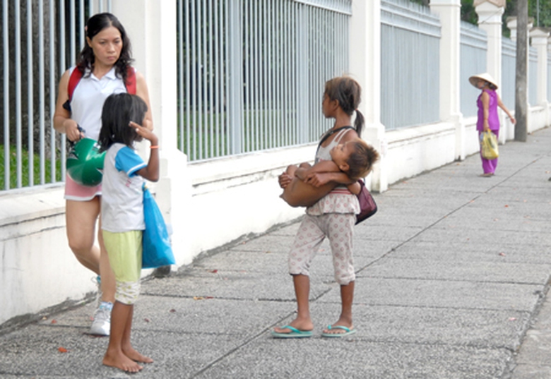 Trẻ em ăn xin đang ch&egrave;o k&eacute;o một người đi đường tại TP HCM 