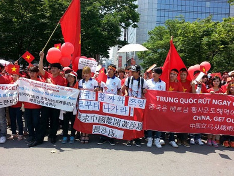 Tại Busan, s&aacute;ng 18/5, khoảng 1.200 người Việt Nam đ&atilde; c&oacute; mặt tại c&ocirc;ng vi&ecirc;n trước cửa nh&agrave; ga Busan, mặc &aacute;o cờ đỏ sao v&agrave;ng, cầm cờ v&agrave; giơ cao những tấm biểu ngữ y&ecirc;u cầu Trung Quốc r&uacute;t gi&agrave;n khoan ra khỏi Việt Nam được thể hiện bằng tiếng Việt, tiếng Anh v&agrave; tiếng H&agrave;n. (Ảnh: Cộng đồng người Việt Nam tại H&agrave;n Quốc)