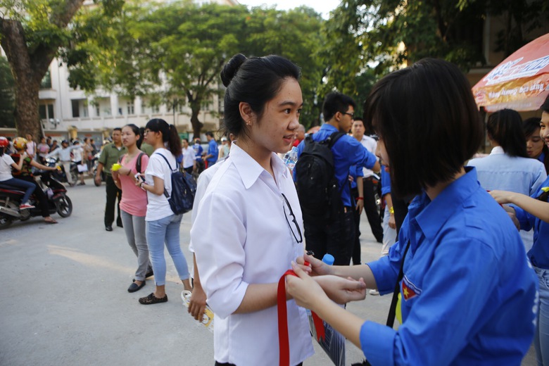 Một sinh vi&ecirc;n t&igrave;nh nguyện đang thắt chiếc d&acirc;y đỏ may mắn động vi&ecirc;n tinh thần c&aacute;c sĩ tử trước khi v&agrave;o trường thi.