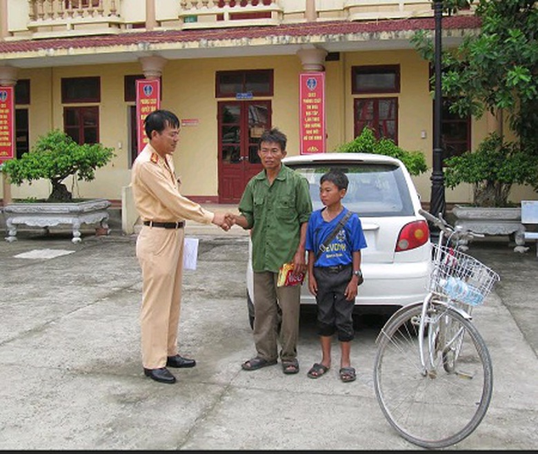 Đại diện Ph&ograve;ng CSGT Quảng B&igrave;nh b&agrave;n giao em Đạt cho gia đ&igrave;nh