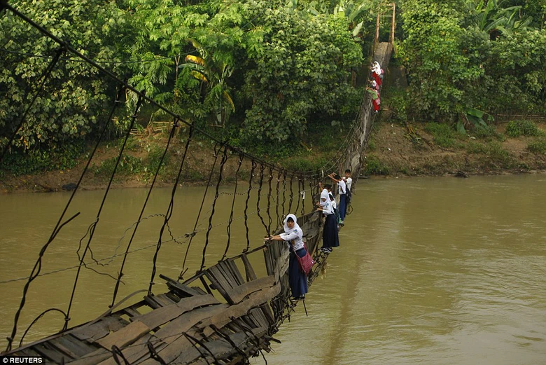 Học sinh tại Indonesia b&aacute;m c&aacute;c thanh sắt tr&ecirc;n c&acirc;y cầu bị g&atilde;y vượt s&ocirc;ng Ciherang, gần l&agrave;ng Lebak Regency.