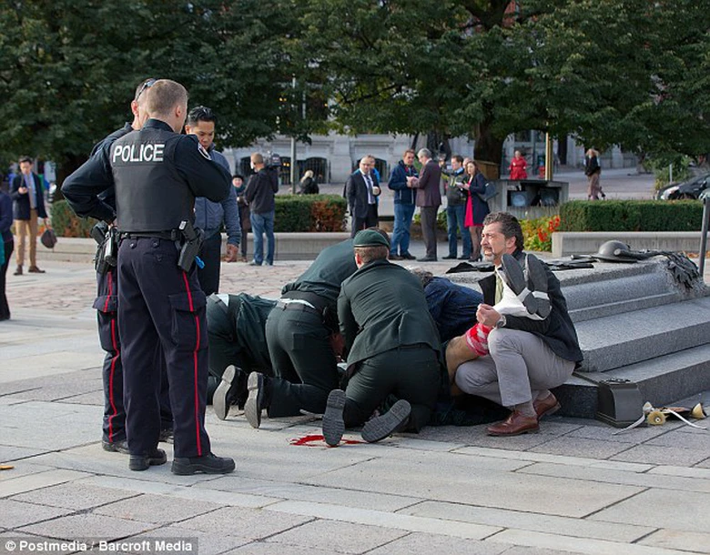 Mọi người sơ cứu cho người l&iacute;nh bị bắn khi đang đứng g&aacute;c tại đ&agrave;i tưởng niệm, nhưng do vết thương qu&aacute; nặng anh đ&atilde; kh&ocirc;ng qua khỏi