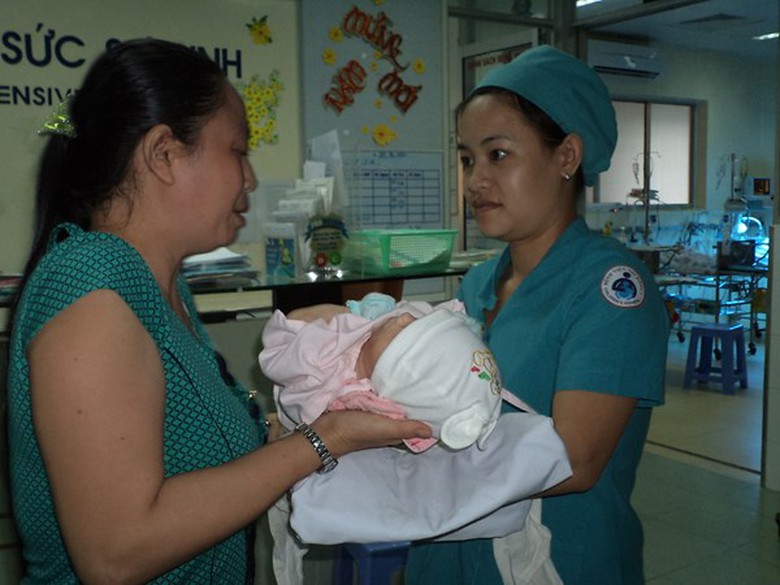 Điều dưỡng đưa b&eacute; cho người nh&agrave; bế cho cha gặp. 