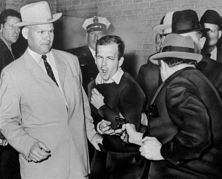 Ng&agrave;y 24/11, Lee Harvey Oswald, thủ phạm &aacute;m s&aacute;t &ocirc;ng Kennedy, bị Jack Ruby, một chủ hộp đ&ecirc;m, bắn khi Oswald đang chuyển trại giam. Xung quanh Oswald l&agrave; những cảnh s&aacute;t mặc thường phục.