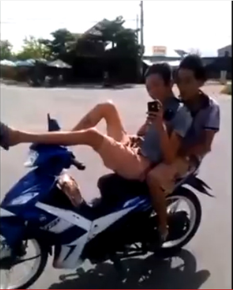 Hai đối tượng điều khiển xe bằng ch&acirc;n, tay chụp ảnh tự sướng. Ảnh cắt từ clip