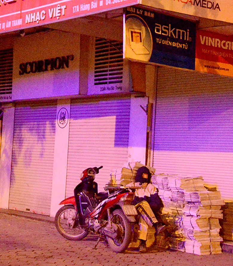 Anh Ch&iacute;nh h&agrave;nh nghề rao b&aacute;o đang co ro trong giấc ngủ vội trước khi binh minh. Anh cố gắng chợp mắt ngay vỉa h&egrave; để giao b&aacute;o