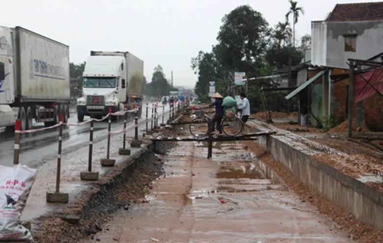 Trong khi nhà th&acirc;̀u thi c&ocirc;ng dàn trải&hellip;gặp khó khi trời mưa, r&acirc;́t nhi&ecirc;̀u h&ocirc;̣ d&acirc;n phải bắc c&acirc;̀u làm l&ocirc;́i đi từ nhà ra QL1