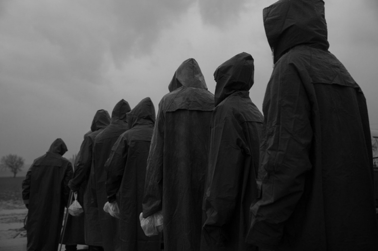 Người tị nạn mặc áo mưa xếp hàng chờ