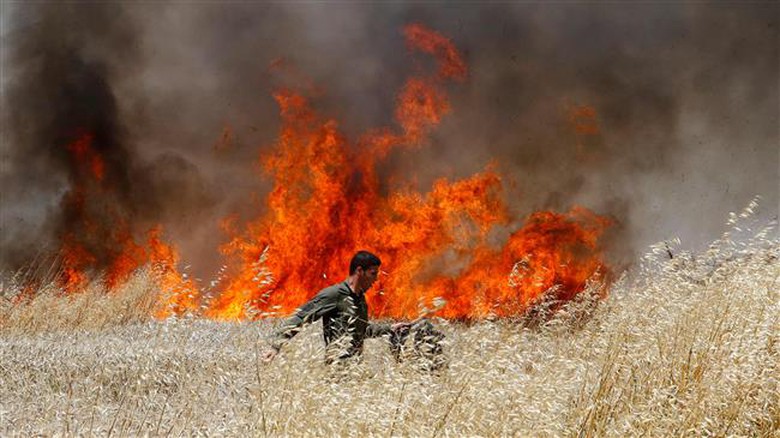 Một binh l&iacute;nh Israel cố gắng dập lửa lớn tr&ecirc;n c&aacute;nh