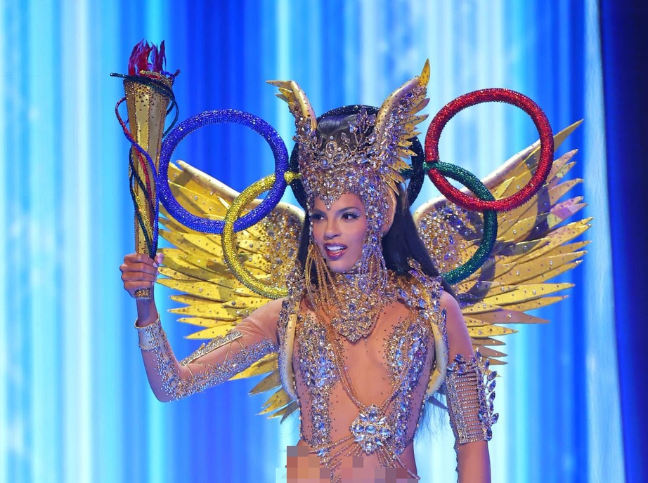 Trang phục d&acirc;n tộc của đại diện Curacao sử dụng vải xuy&ecirc;n thấu kết hợp c&ugrave;ng nhiều loại đ&aacute; để che chắn một v&agrave;i điểm tr&ecirc;n cơ thể. C&ograve;n phần th&acirc;n dưới, c&ocirc; n&agrave;ng chỉ b&ocirc;i lớp m&agrave;u h&oacute;a trang v&agrave;ng đồng, do đ&oacute;, Kim Rossen bị lộ gần hết h&igrave;nh thể khi tr&igrave;nh diễn. Trang phục được lấy cảm hứng từ những vận động vi&ecirc;n Curacao mong muốn được thi đấu tại Thế vận hội Olympic. Bộ c&aacute;nh thể hiện sự quyết t&acirc;m v&agrave; ki&ecirc;n cường, pha trộn c&ugrave;ng vẻ đẹp vương giả với biểu tượng của thể thao.