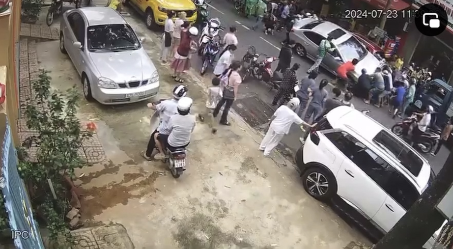 Người d&acirc;n khi&ecirc;ng xe cứu c&ocirc; g&aacute;i dưới gầm xe &ocirc; t&ocirc;. (Ảnh cắt từ clip)