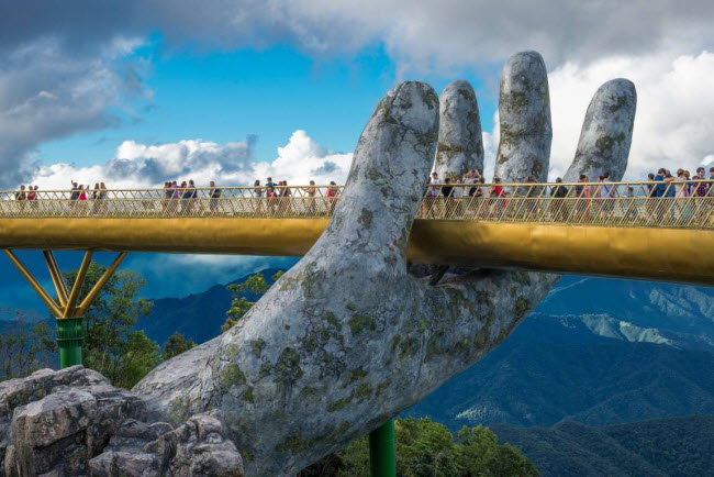 Cầu V&agrave;ng, Việt Nam: Cầu d&agrave;nh cho người đi bộ tại khu du lịch B&agrave; Na Hills g&acirc;y ấn tượng với trụ được thiết kế giống hai b&agrave;n tay khổng lồ. Từ tr&ecirc;n c&acirc;y cầu, du kh&aacute;ch c&oacute; thể chi&ecirc;m ngưỡng phong cảnh n&uacute;i rừng tuyệt đẹp.