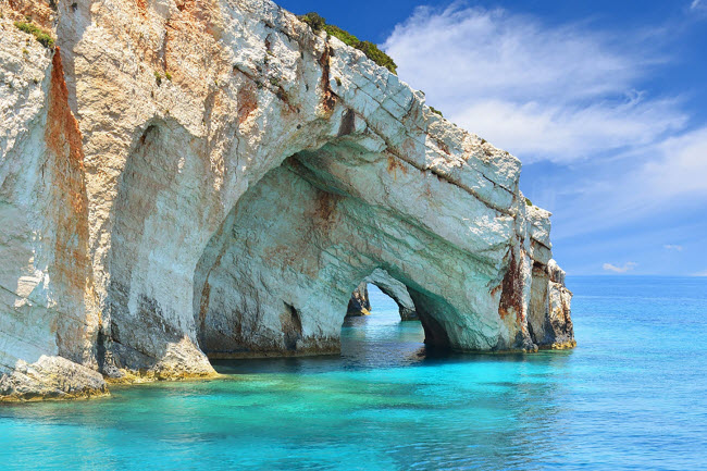 Blue, Hi Lạp: Nằm tr&ecirc;n v&aacute;ch n&uacute;i ở ph&iacute;a bắc của đảo Zakynthos, hang Blue g&acirc;y ấn tượng với v&aacute;ch đ&aacute; voi trắng phản chiếu m&agrave;u xanh từ nước biển. Nơi du đ&acirc;y thu h&uacute;t h&agrave;ng ngh&igrave;n du kh&aacute;ch mỗi năm.

