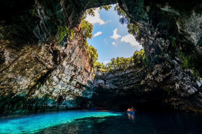 Melissani, Hi Lạp: Nằm tr&ecirc;n h&ograve;n đảo Kefalonia, hang động Melissani chia l&agrave;m hai phần. Phần động mở c&oacute; giếng trời tr&ecirc;n đỉnh gi&uacute;p &aacute;nh s&aacute;ng lọt v&agrave;o b&ecirc;n trong, phần động c&ograve;n lại rất tối v&agrave; được bao phủ bởi r&ecirc;u, tảo v&agrave; măng đ&aacute;.