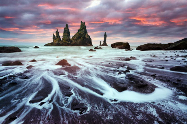 Reynisdrangar, Iceland:&nbsp;B&atilde;i biển gần ng&ocirc;i l&agrave;ng V&iacute;k &iacute; M&yacute;rdal g&acirc;y ấn tượng với n&uacute;i đ&aacute; bazan bao gồm 3 đỉnh cao 66m. Theo truyền thuyết Iceland, ch&uacute;ng l&agrave; h&agrave;i cốt của những người khổng lồ xấu số.
