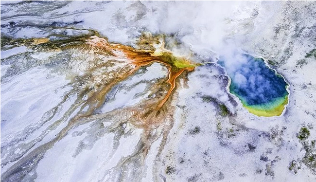 Lửa v&agrave; băng: Bức ảnh chụp từ C&ocirc;ng vi&ecirc;n Quốc gia Yellowstone ở Mỹ. Bề mặt băng gi&aacute; phủ l&ecirc;n những mảng&nbsp;m&agrave;u sắc rực rỡ khi nước lưu huỳnh n&oacute;ng chảy qua tuyết.&nbsp;