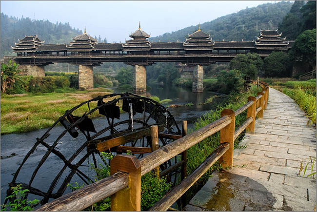 Đứng tr&ecirc;n cầu, bạn c&oacute; thể nh&igrave;n thấy b&aacute;nh xe nước lớn quay chậm, những ng&ocirc;i nh&agrave; của tộc Đồng nằm dọc b&ecirc;n s&ocirc;ng v&agrave; gần n&uacute;i.