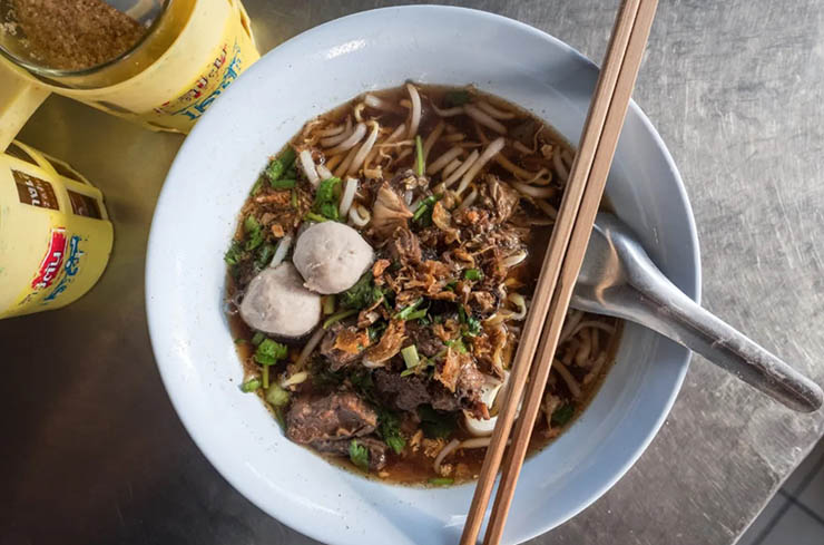 11. Kuaytiaw l&agrave; m&oacute;n mỳ&nbsp;được&nbsp;b&agrave;y b&aacute;n nhiều ở ven đường, nước d&ugrave;ng c&oacute; m&agrave;u n&acirc;u mặn ngọt v&agrave; ăn k&egrave;m với c&aacute;c loại thịt t&ugrave;y chọn, th&ecirc;m một &iacute;t rau như gi&aacute; đỗ.
