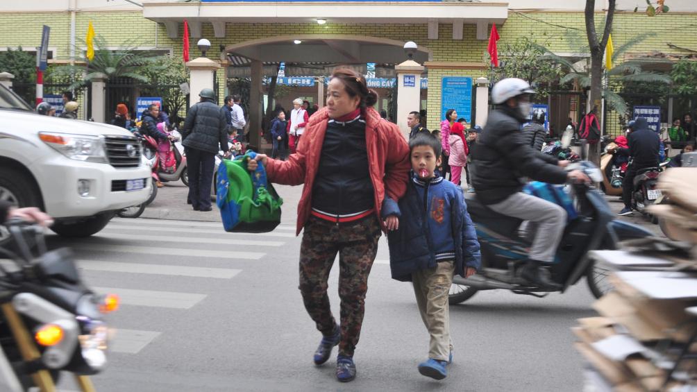 Phụ huynh dắt con sang đường kh&ocirc;ng đi v&agrave;o vạch kẻ d&agrave;nh cho người đi bộ...