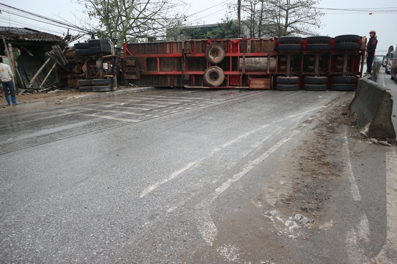 Chiếc xe container sau khi t&ocirc;ng v&agrave;o 2 xe &ocirc; t&ocirc; th&igrave; lao v&agrave;o dải ph&acirc;n c&aacute;ch h&uacute;c g&atilde;y biển b&aacute;o rồi lao v&agrave;o nh&agrave; d&acirc;n lật nghi&ecirc;ng