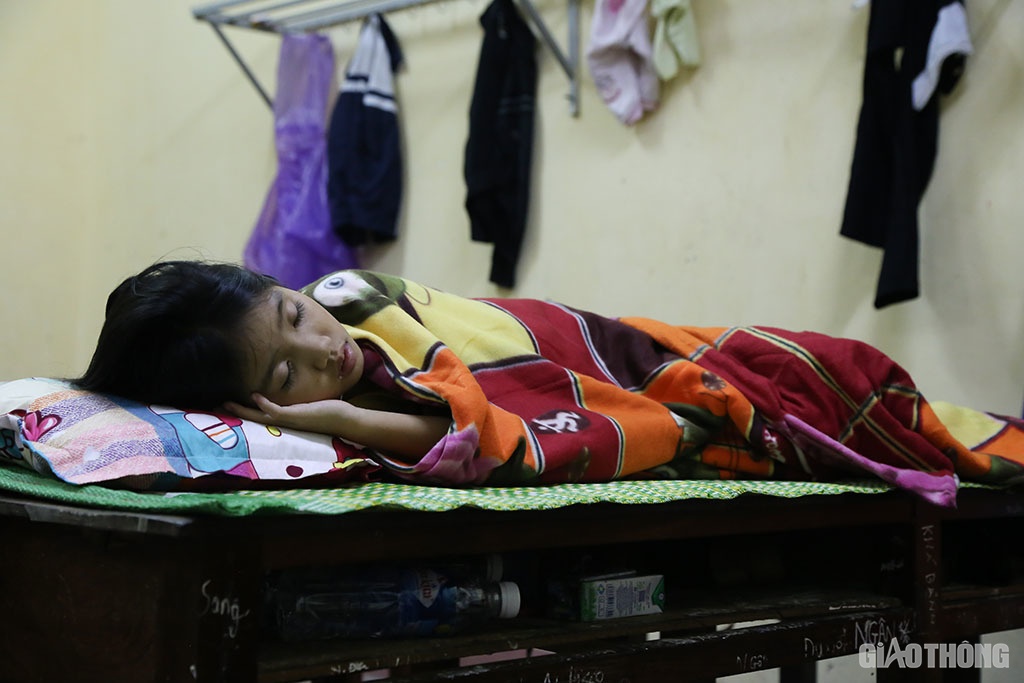 Một b&eacute; g&aacute;i ở ph&ograve;ng kh&aacute;c ngủ ngon l&agrave;nh tr&ecirc;n chiếc giường được k&ecirc; từ 2 c&aacute;i b&agrave;n học.