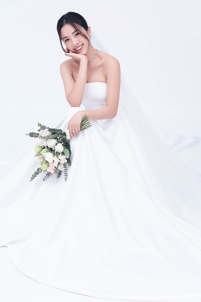 Th&uacute;y An lựa chọn chiếc đầm cưới trắng tinh kh&ocirc;i cho ng&agrave;y trọng đại. Kiểu d&aacute;ng c&uacute;p ngực c&ugrave;ng th&acirc;n v&aacute;y x&ograve;e, kết hợp layout t&oacute;c nhẹ nh&agrave;ng gi&uacute;p t&ocirc;n l&ecirc;n n&eacute;t dịu d&agrave;ng, nữ t&iacute;nh,