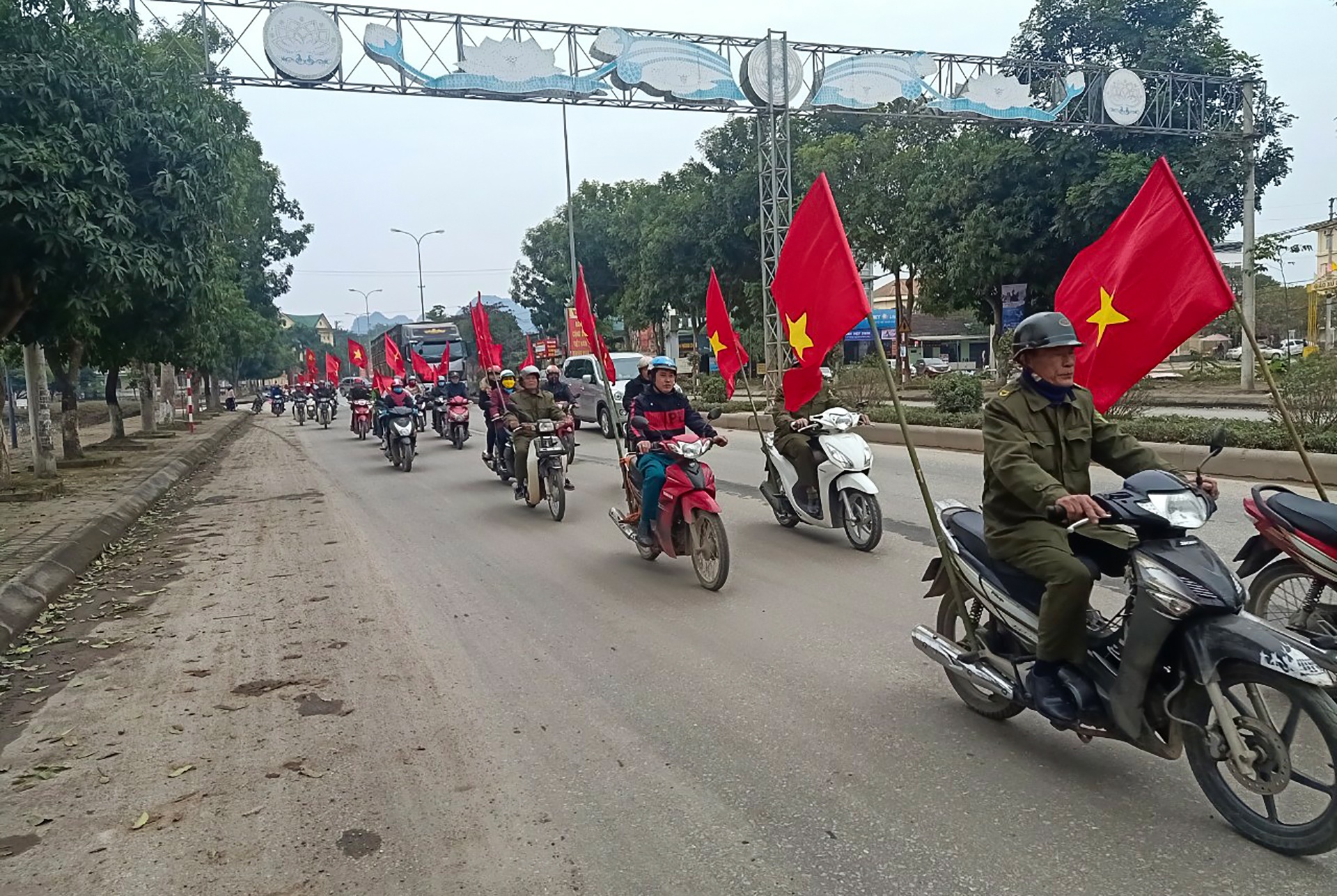 Người d&acirc;n Anh Sơn mang theo cờ Đảng v&agrave; cờ Tổ quốc diễu h&agrave;nh tr&ecirc;n đường